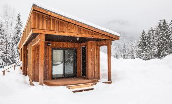 a small wooden cabin is covered in snow with a deck and a glass door at Boulder Mountain Resort
