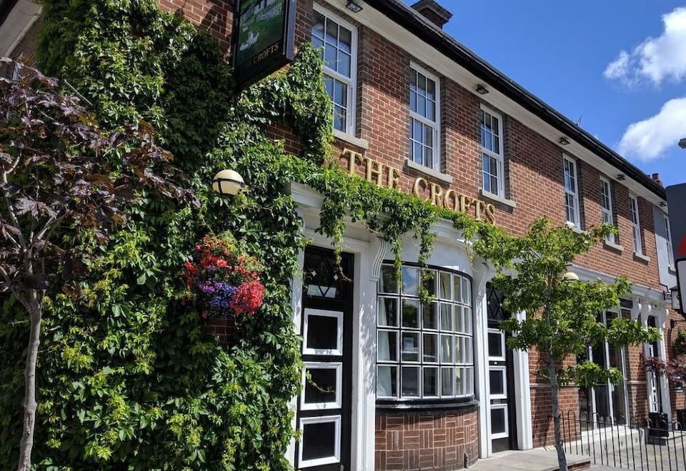 "a brick building with ivy on its exterior , and the name "" the crown "" is visible above the sign" at Crofts Hotel