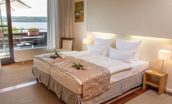 a large bed with a floral arrangement on it is in a room with a window at Seehotel Leoni