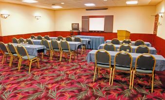 a conference room with chairs arranged in rows and a projector screen on the wall at Best Western Plus Butte Plaza Inn