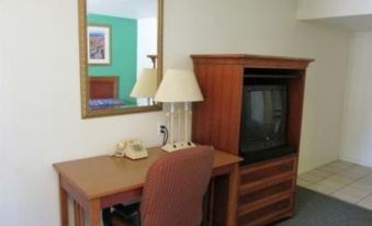 a hotel room with a desk , chair , and a television mounted on the wall at Village Inn