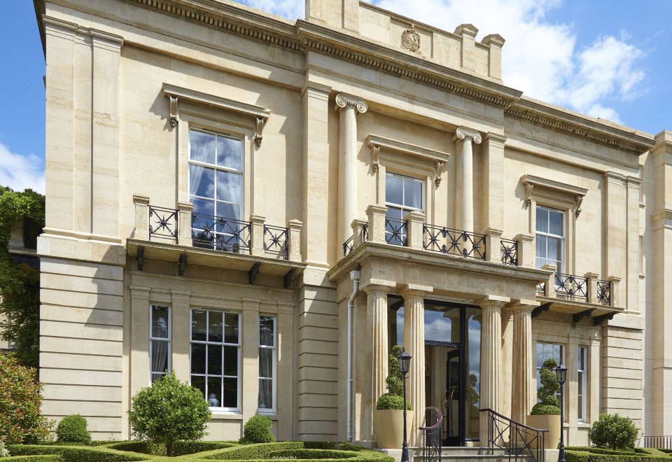 a large , beige - colored building with white columns and a black railing is shown in the image at Macdonald Bath Spa Hotel