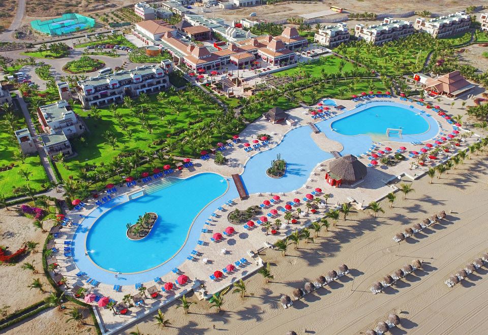 aerial view of a resort with multiple swimming pools , beach umbrellas , and sun loungers on the sand at Royal Decameron Punta SAL - All Inclusive