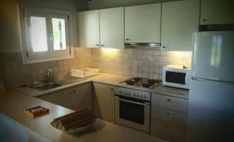 a kitchen with white cabinets and appliances , including a stove , oven , microwave , and refrigerator , under a wooden ceiling at Skiathos Holidays Suites & Villas