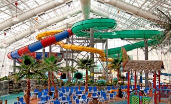 a large indoor water park with multiple slides and pools , surrounded by blue umbrellas and chairs at Residence Inn Rapid City