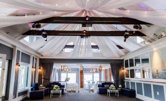 a large , open room with a high ceiling and white drapes hanging from it , filled with comfortable seating arrangements at Danfords Hotel & Marina