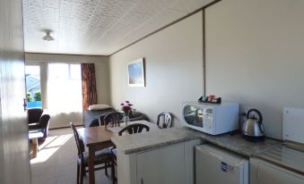 a kitchen and dining area with a table , chairs , microwave , coffee maker , refrigerator , and stove at Anchor Motel