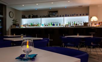 a bar with blue chairs and white tables , a glass of wine on one table at Daiwa Roynet Hotel Numazu