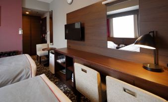 a hotel room with a bed , desk , and tv , as well as a view of the city through a window at Hotel Monte Hermana Fukuoka