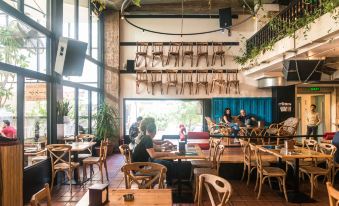 a modern restaurant with wooden tables and chairs , people sitting at the bar , and hanging plants at Hamra Urban Gardens