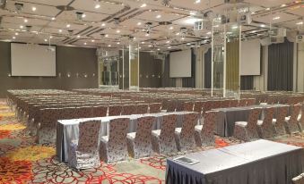 a large conference room with multiple rows of chairs arranged in a semicircle , and a podium at the front of the room at Platinum Hotel