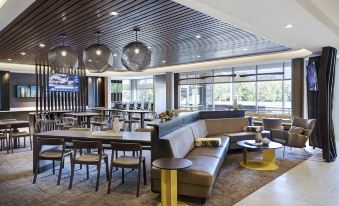 a modern and spacious restaurant with wooden ceiling , large windows , comfortable seating , and yellow tables at SpringHill Suites Columbia