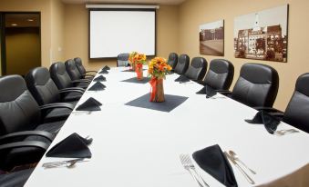 a conference room with a long table , black chairs , and a projector screen , decorated with flowers at Holiday Home Park Central Port Arthur