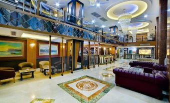 a large hotel lobby with high ceilings , multiple seating areas , and a staircase leading to the second floor at New Marathon Hotel