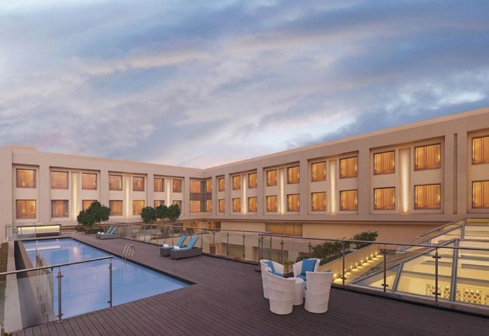 a modern hotel with a swimming pool , surrounded by trees and lit up at night at DoubleTree by Hilton Agra
