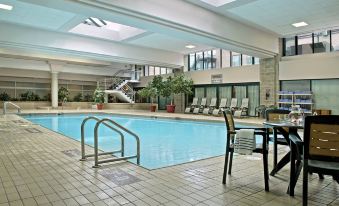an indoor swimming pool surrounded by a hotel lobby , with people enjoying their time in the pool at Halifax Marriott Harbourfront Hotel