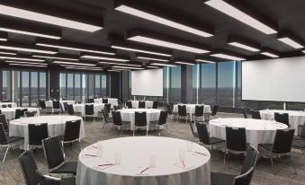 a large conference room with multiple round tables and chairs arranged for a meeting or event at Aloft Perth