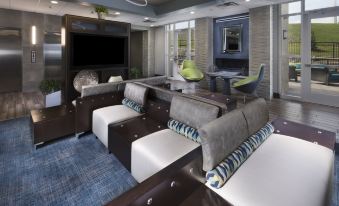 a modern living room with a large flat - screen tv mounted on the wall , surrounded by couches and chairs at Holiday Inn & Suites Arden - Asheville Airport