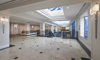 a large , open room with white walls and a marble floor has a skylight above at Sheraton Parkway Toronto North Hotel & Suites