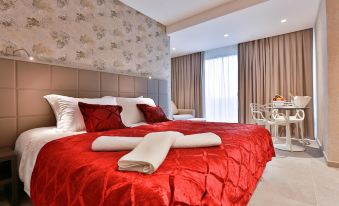 a large bed with a red blanket and white towels is in a room with a window at Monteverde Hotel