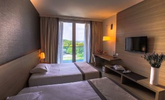 a hotel room with two beds , a desk , and a window overlooking a body of water at Quality Hotel San Martino