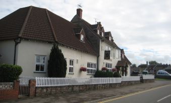 a white building with brown roof and red trim , situated on the side of a road at Malt House