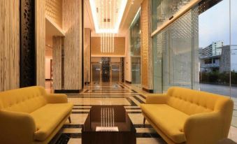 a luxurious lobby with yellow couches , marble floors , and large windows , providing an inviting atmosphere for guests at Hompton Hotel by The Beach