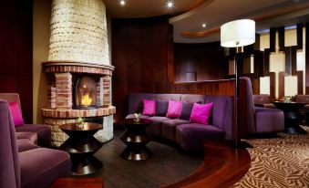 a cozy living room with a purple couch and a fireplace , creating a warm and inviting atmosphere at Sheraton Poznan Hotel