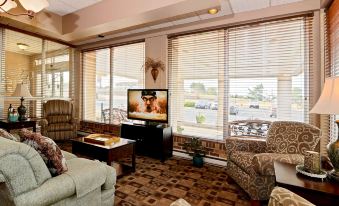 a cozy living room with a large flat - screen tv mounted on the wall , a couch , and a chair at Best Western Tomah Hotel