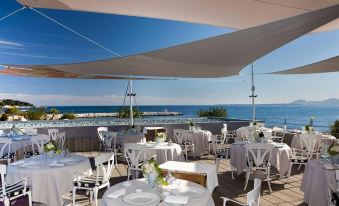 an outdoor dining area with tables and chairs set up for a group of people to enjoy a meal at Cap d'Antibes Beach Hotel