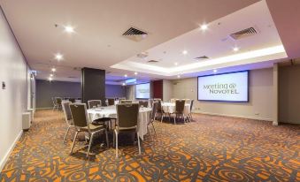 a conference room with a large screen and tables set up for a meeting or event at Novotel Canberra