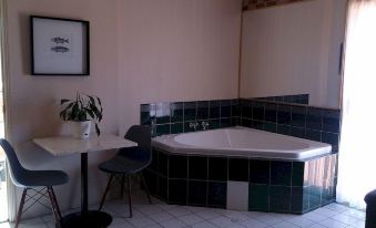 a bathroom with a large bathtub surrounded by green tile walls , creating a unique and cozy atmosphere at Airport Clayfield Motel