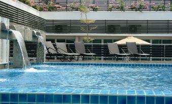 an outdoor swimming pool surrounded by chairs and umbrellas , with a waterfall feature in the middle of the pool at Hotel Sfera