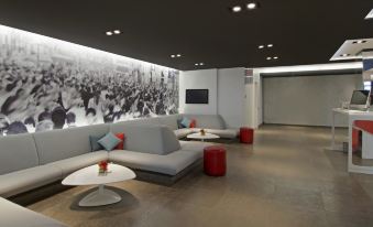 a modern lounge area with gray couches , red ottomans , and a large black and white mural on the wall at Novotel Montreal Center