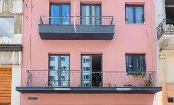 a pink building with balconies and awnings is shown in front of other buildings in the city at Lux Hotel