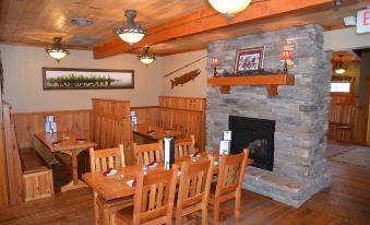 a cozy dining room with wooden furniture , including a table and chairs , and a fireplace at Cranberry Inn