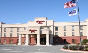 "a large building with a red and white sign that says "" hampton inn "" is surrounded by flags and parking lot" at Hampton Inn Moultrie