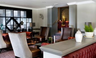 a modern living room with various seating options , including chairs and couches , arranged around a coffee table at Macdonald Berystede Hotel & Spa