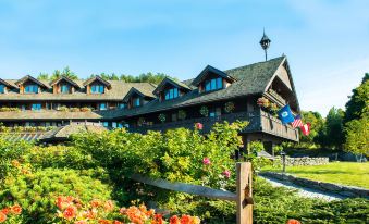 a large wooden building surrounded by a lush garden , with numerous potted plants and flowers at Trapp Family Lodge