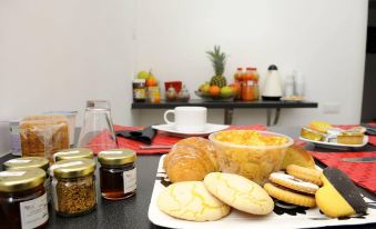 a dining table with a variety of food items , including bread , crackers , and a cup of tea at Magic Rainbow