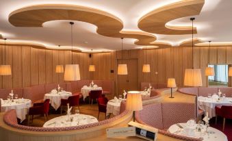 a modern restaurant with wooden walls and curved ceiling , featuring several dining tables and chairs at Alpin Panorama Hotel Hubertus