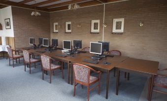 a room with multiple computer desks and chairs arranged in rows , creating a workspace for students at Fletcher Hotel Restaurant de Gelderse Poort