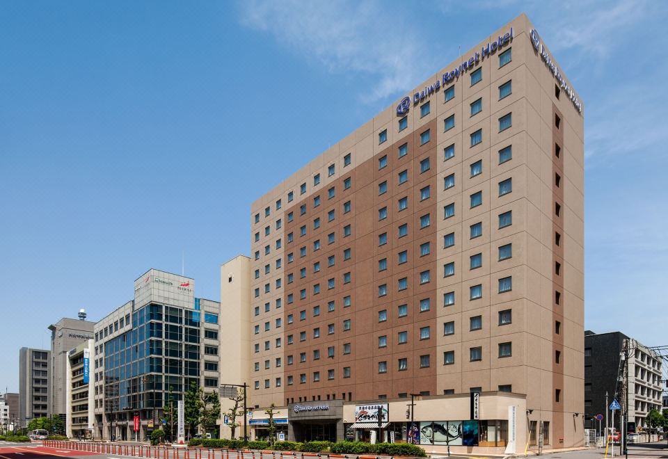 "a large , beige - colored building with the logo "" the new american "" on it , standing next to other buildings in a city setting" at Daiwa Roynet Hotel Oita