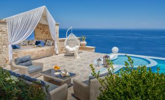 a luxurious outdoor living area with a pool , lounge chairs , and a hanging chair overlooking the ocean at Emerald Villas & Suites - the Finest Hotels of the World