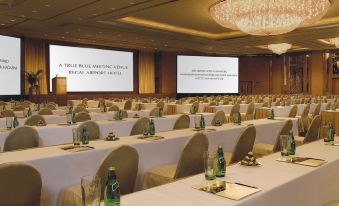 A spacious room is set up with tables and chairs for events or conferences at Regal Airport Hotel