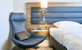 a modern hotel room with a bed , nightstand , and chair , along with some toiletries on the nightstand at Moxy Edinburgh Airport