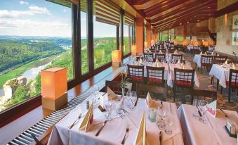 a large dining room with tables and chairs arranged for a group of people to enjoy a meal at Berghotel Bastei