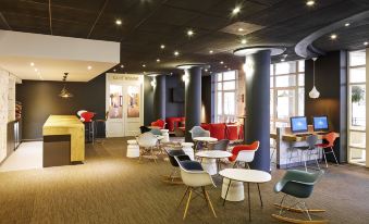 a modern lounge area with several chairs , couches , and tables arranged in a lounge - like setting at Ibis London Greenwich