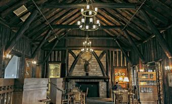 a rustic wooden interior with exposed brick walls , exposed beams , and a chandelier hanging from the ceiling at Pine Mountain State Resort Park