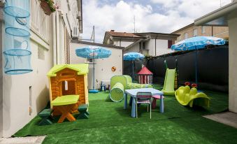 a colorful outdoor play area with various children 's toys , including a slide , swings , and a table at Hotel Milano